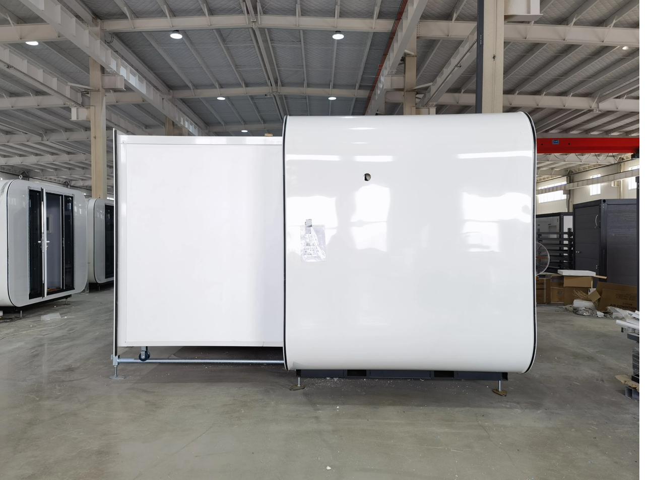 Expandable 20ft tiny house exterior side view — modern white curved-shell pod in the Cambridge facility