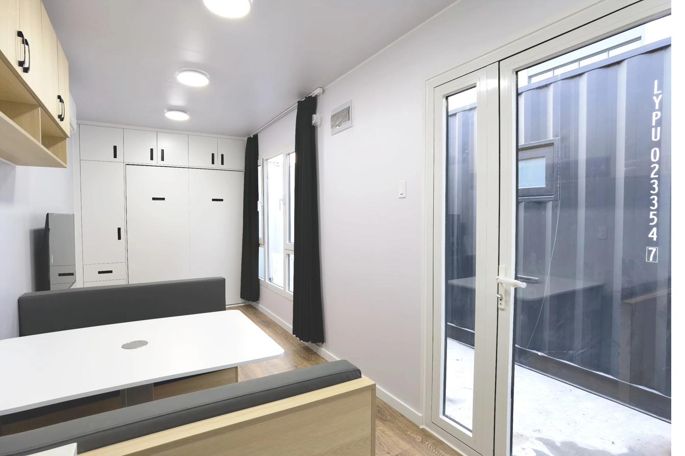 Premium 40ft tiny house entrance — banquette dining area with Murphy bed storage and exterior container door
